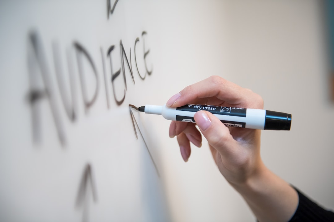 Une main de femme inscrit le mot audience sur un tableau blanc, avec des flèches.